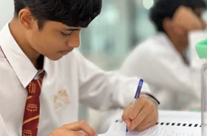 international student writing on paper at his desk.